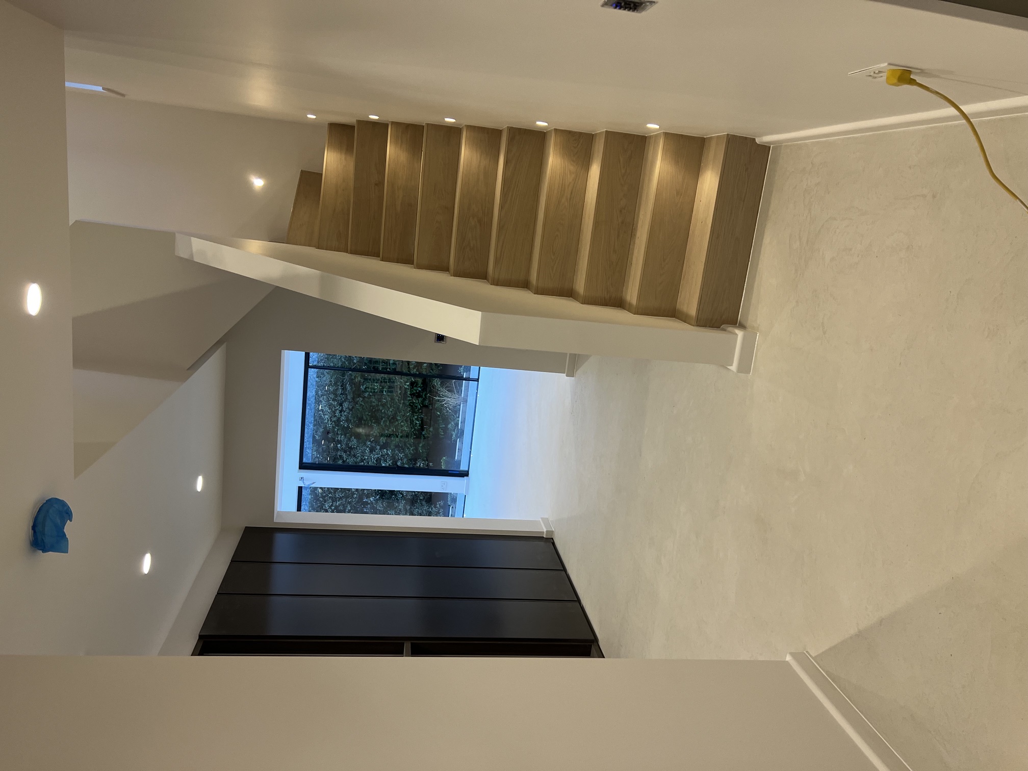 Hallway with oak stairs, black joinery and garden views